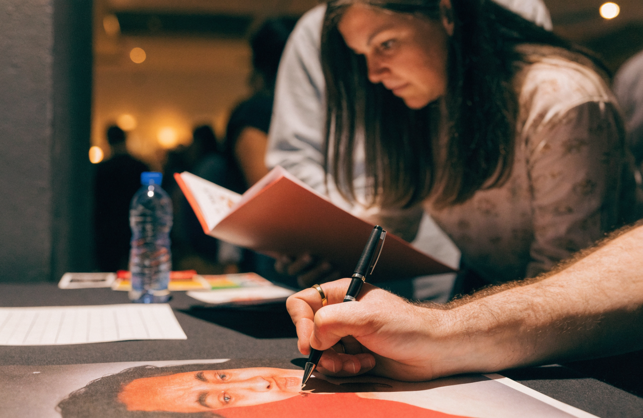 A fan getting an autograph at a signing table at an event